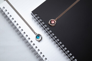 Obraz premium Silver chain necklaces with blue and pink diamond pendant on white office desk