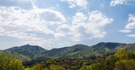 Nature landscape on a fine day. Mountains covered with blue sky, puffy clouds and green vegetation.