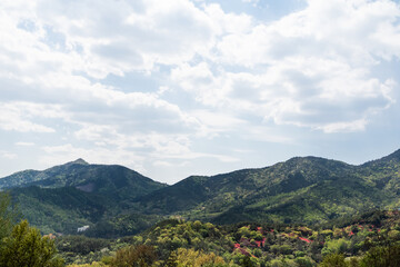 Fototapeta premium Nature landscape on a fine day. Mountains covered with blue sky, puffy clouds and green vegetation.