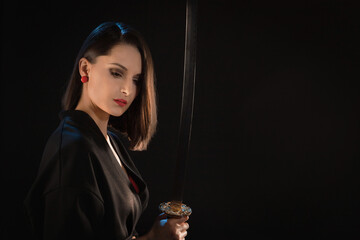 Portrait of a pensive young warrior woman with an Asian sword