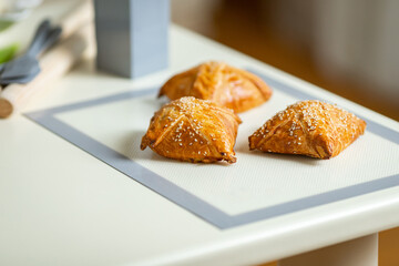 Fresh samsa on a baking mat on the kitchen table