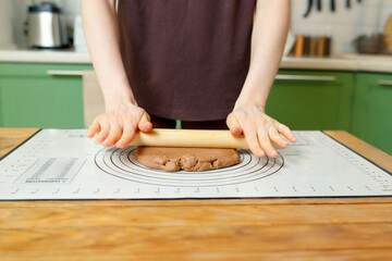 Rolling out shortcrust pastry on a silicone baking mat on a wooden table with copy space