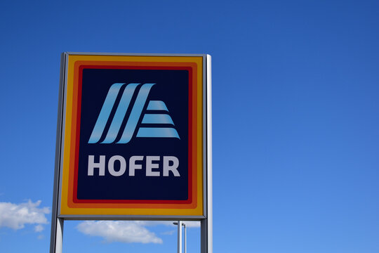 Hofer Firmenschild in Blau und Orange vor blauem Himmel im Fr&uuml;hling