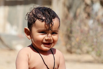 Photo of A small cute Indian Hindu child expresses happiness while taking a bath with unclothed