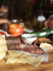 Peppercorn Salami on Tray With English and Irish Cheese, Sliced Apples and Spices in Rustic Kitchen