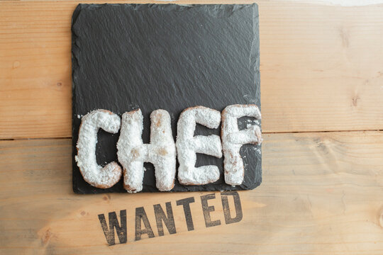 pastry chef wanted, cookie letters powdered with sugar on a black stone tile. - Powered by Adobe