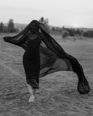 Woman in black dress dancing with flying fabric