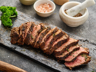 Grilled sliced beef steak on cutting board over grey table. Beef tenderloin steak. Filet Mignon recipe.
