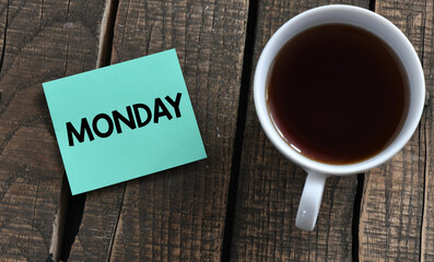 The word MONDAY on a small piece of paper and a wooden table.
