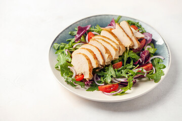 Chicken breast on the leaves arugula with radichio, tomatoes and onions. Balanced lunch.