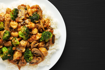 Homemade Chicken Veggie Stir Fry with White Rice on a black background, top view. Copy space.