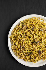 Homemade Spinach Mushroom Pesto Spaghetti on a Plate on a black background, top view. Flat lay, overhead, from above. Space for text.