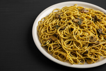 Homemade Spinach Mushroom Pesto Spaghetti on a Plate on a black surface, side view. Copy space.