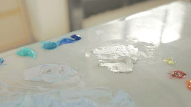 Artist palette with acrylic colours reveals spatula in hand