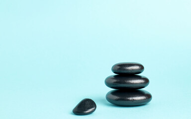 Fototapeta na wymiar A stack of black zen balance stones on a blue background. The concept of a SPA center. A stage for promotion, sale, presentation or cosmetics. Copy space
