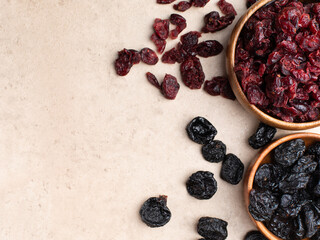 Healthy dried fruit, cranberry, prunes in a wooden bowl top view flatlay. Tasty food photo with copy space banner background.