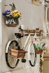 Old bicycle hanging on a white stone wall and used to hang vases and lantern in the alleys or...