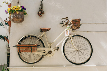 Fototapeta na wymiar Old bicycle hanging on a white stone wall and used to hang vases and lantern in the alleys or narrow street of Mottola, Taranto, Puglia, Italy
