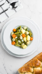Vegetable stew with potato, carrot, artichokes and cauliflower in a tabe with bread and cutlery
