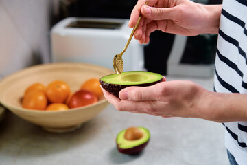 Woman hold fresh ripe avocado and peeling it with spoon, Healthy food and dieting concept, Organic product