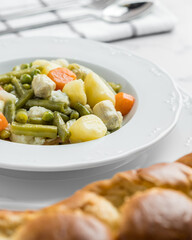 Vegetable stew with potato, carrot, artichokes and cauliflower in a tabe with bread and cutlery