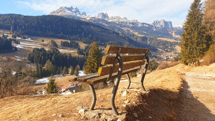 Lonely bench overlooking the mountain landscape of the city of Moena.
