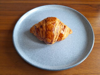 Fresh croissant on the plate with brown background, 