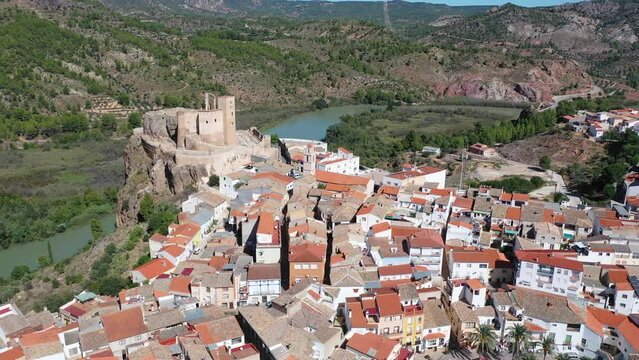 Picturesque autumn landscape with small Spanish town of Cofrentes located in mountainous area of Valencia province overlooking ancient fortified castle