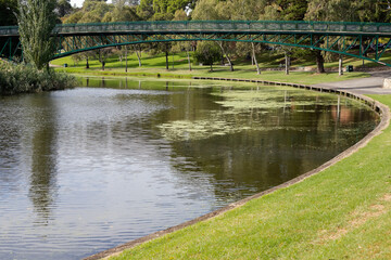 Landscape with a bridge over the river in the city park surrounded by green trees