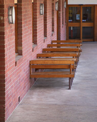 Fototapeta na wymiar Row of wooden benches along a red brick wall