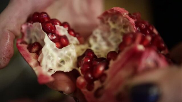 Peeling pomegranate. Opening and showing red seed.
