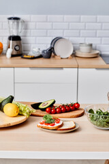 Fresh vegetables on cutting board on table for preparing sandwiches and salad in domestic kitchen