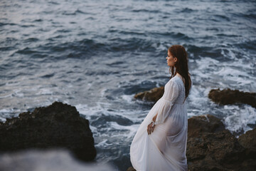 pretty woman in wedding dress landscape cliff ocean wave