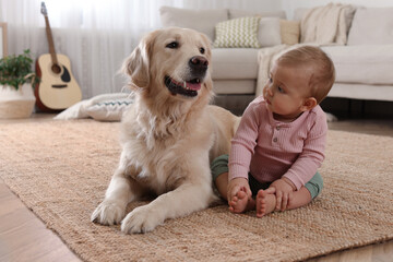 Cute little baby with adorable dog on floor at home