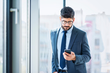 Businessman using mobile phone while standing at the office