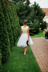 Shoes and garden shears, Sweet pretty girl in a light dress with a tulle skirt in a beautiful garden