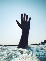 Hand of a drowning man reaching out from the deep cold sea water and asking for help and salvation