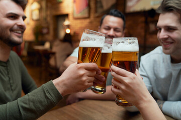 Friends meeting in a pub and clinking beer glasses