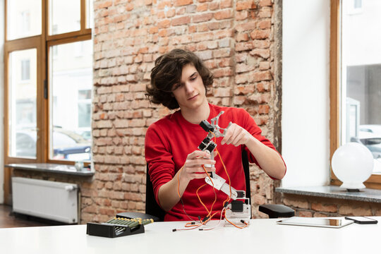 Teenage boy working on robotic arm sitting at table
