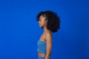 Young woman with Afro hairstyle standing against blue background