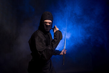 Medieval warrior assassin ninja with sword in aggressive pose in smoke
