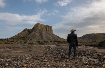 Adult man in cowboy hat in desert against rock and sky