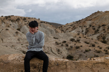 Naklejka na ściany i meble Portrait of teenage Asian boy on oasis of desert against mountain and sky
