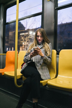 Young woman using mobile phone sitting in tram