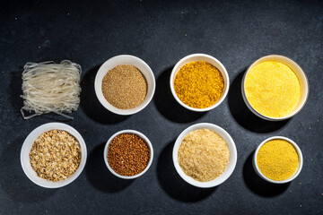 Selection of whole grains gluten free cereals. Set of various non-gluten cereals: rice, buckwheat, corn groats, quinoa, millet, oats, buckwheat, bulgur, porridge, barley, black background copy space