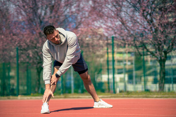 A muscular athlete stretches before a sports training session at a sports stadium