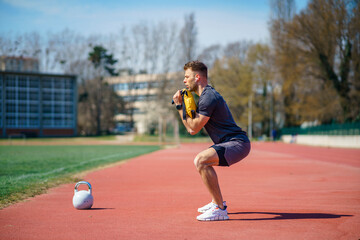Muscular young man exercising with heavy weight bag in the sport stadium. Sporty man working out with heavy weight bag.