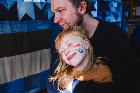 Happy blond girl with father sitting at home
