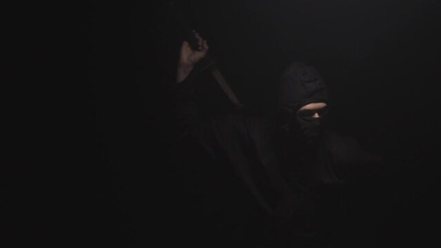 Medieval warrior assassin ninja with sword in aggressive pose in smoke