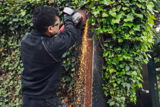 Man using grinder working on metal gate